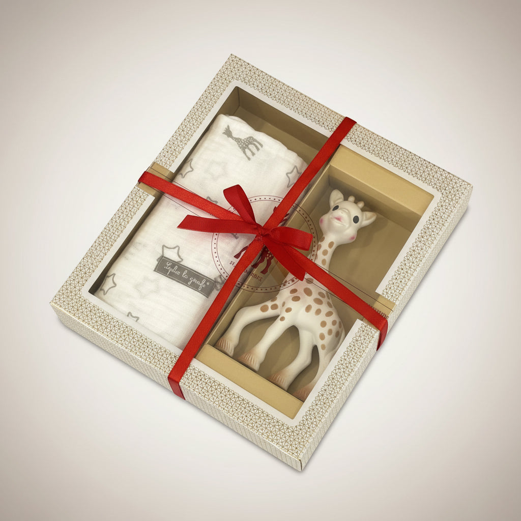 Gift set with a giraffe toy and blanket in a box with a red ribbon on a grey background