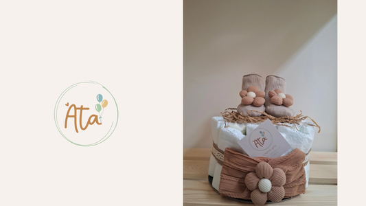 πανότουρτα , πανες σαν τούρτα με κορδέλα με λουλούδι τριγύρω και επάνω από τις πάνες καλτσάκια για νεογέννητα σε σομόν αποχρώσεις και logo