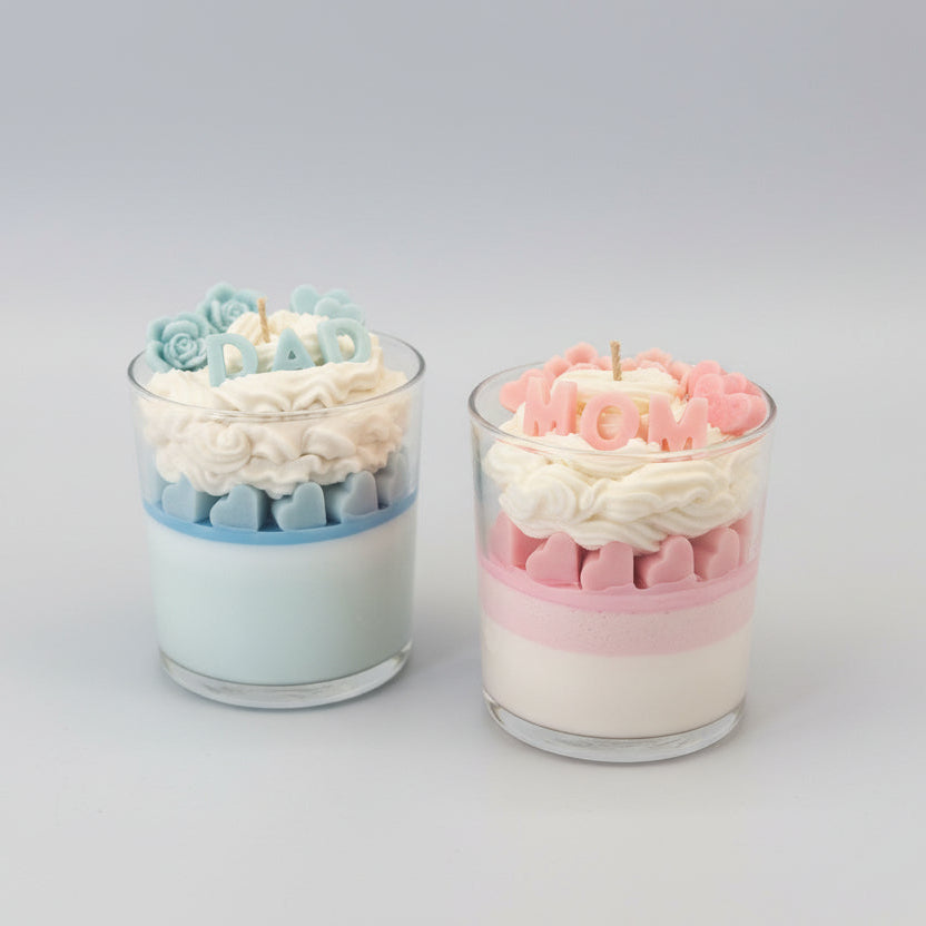 Two decorative candles in glass holders saying mom and dad
