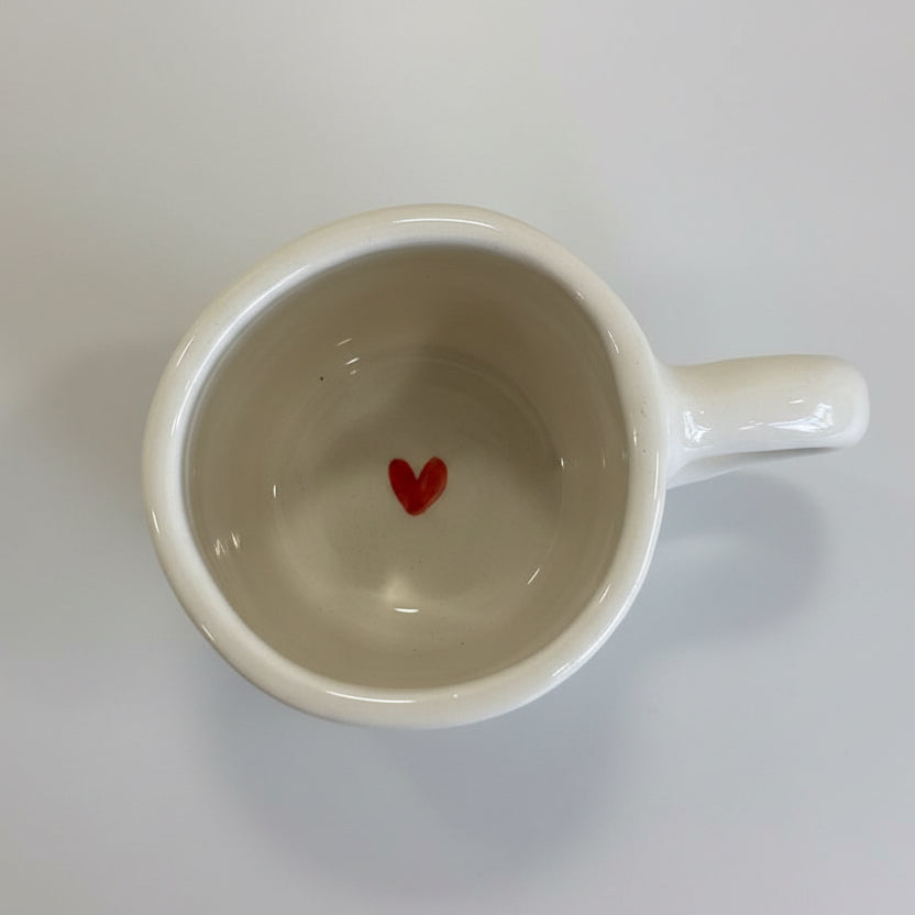 White mug with a red heart on a floral-patterned surface