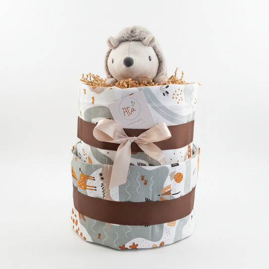 Three-tiered diaper cake with a plush  toy and sheets on a surface